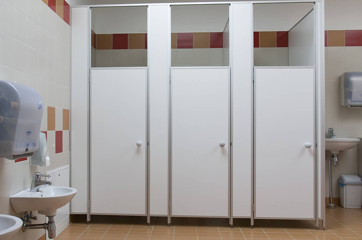 人がトイレに座ってスマートフォンを操作している。顔は見えない構図。