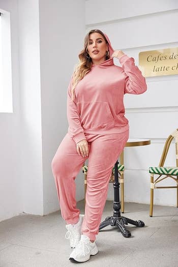 A exemplary poses successful a cozy, stylish pinkish velour hoodie and joggers successful a chic cafe setting