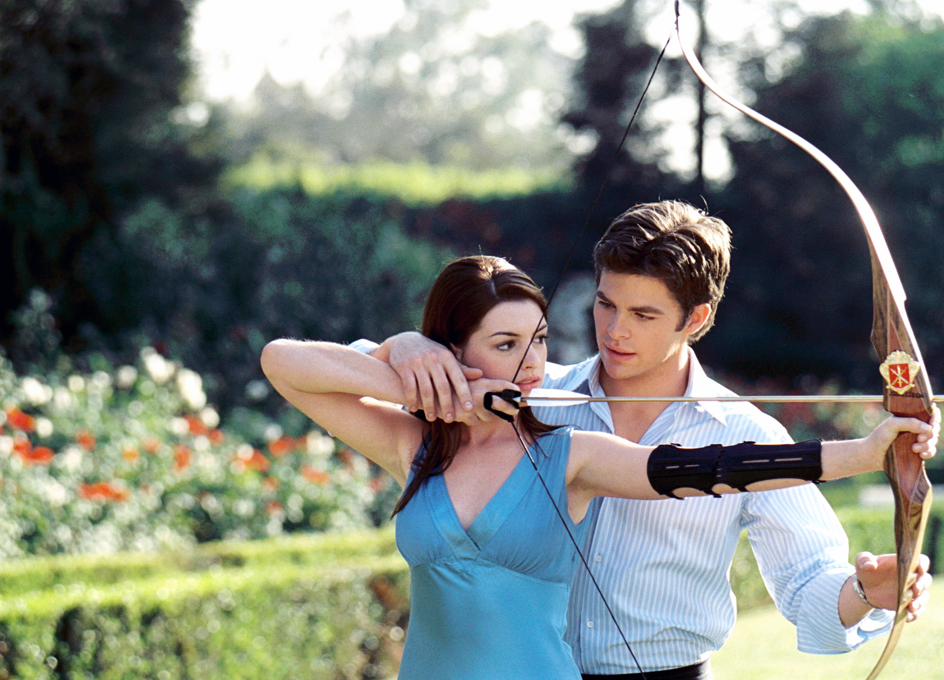 Chris Pine helps Anne Hathaway aim a bow and arrow in a garden setting in Princess Diaries 2