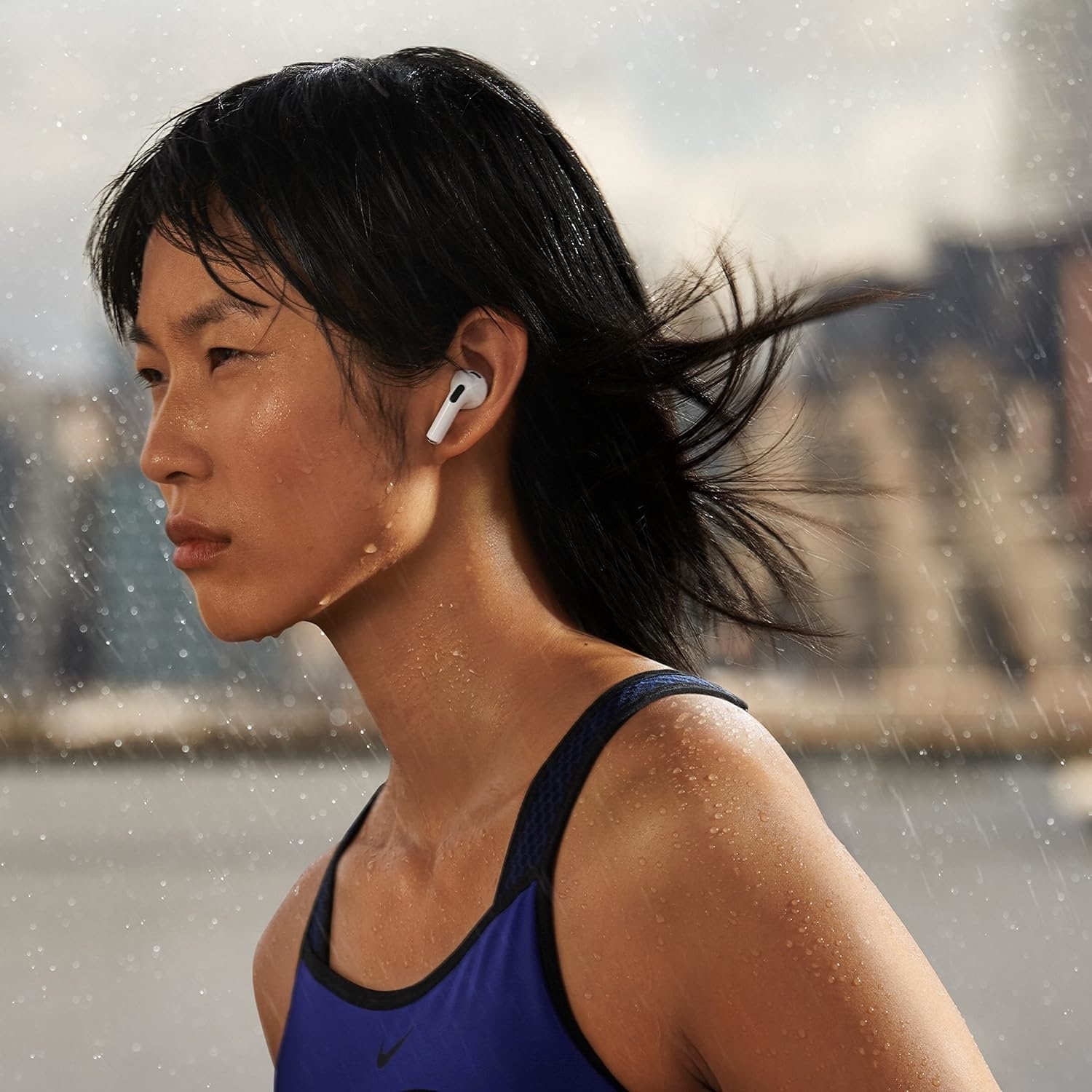 Person running in the rain, wearing wireless earbuds and athletic tank top