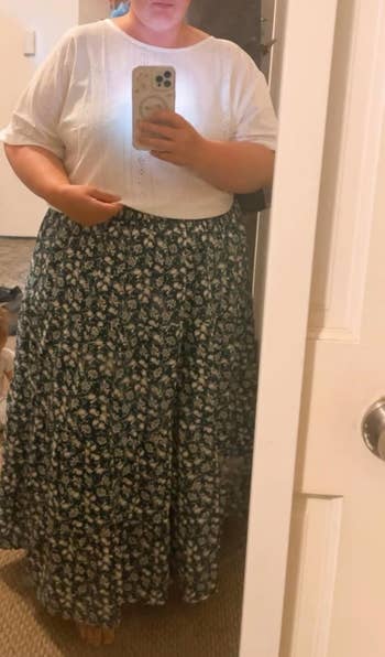 Person taking a reflector selfie wearing a achromatic apical and a long, achromatic floral skirt