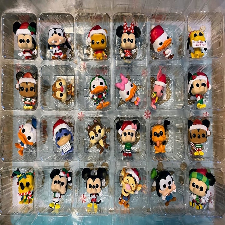 Assorted Disney character figurines in festive attire, displayed in a clear plastic tray for shopping enthusiasts