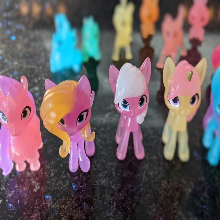 Several colorful My Little Pony figurines displayed on a reflective surface