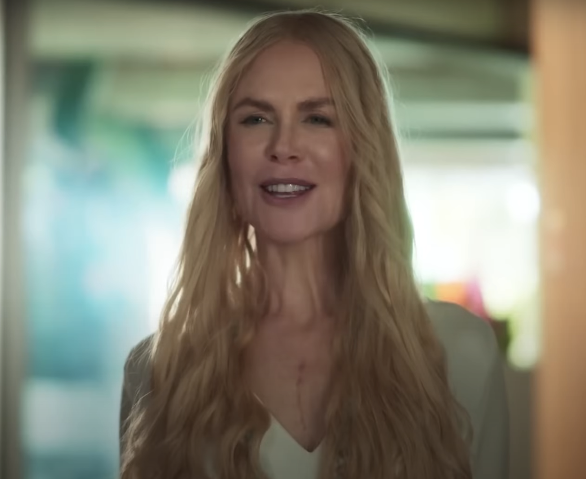 I don't know who this person is, but they have long, wavy hair and are smiling while wearing a casual light blouse