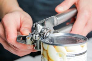 Person using a metal can opener to open a can of food