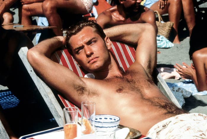 Jude Law lounging on a beach chair, shirtless, with drinks nearby in The Talented Mr Ripley