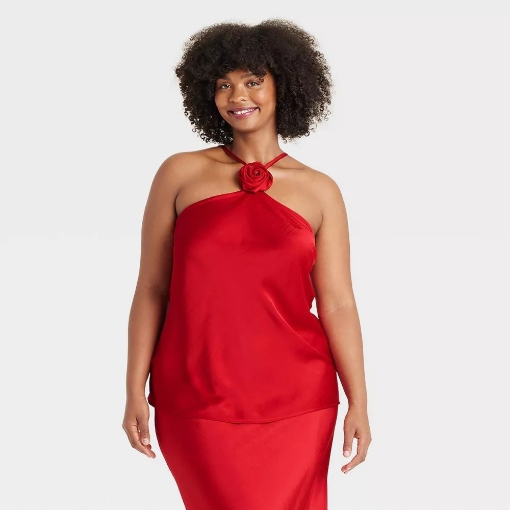 A person modeling a stylish halter-neck dress with a rose detail, suitable for a shopping article