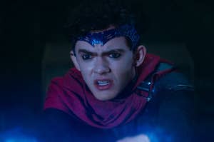 Character wearing a dark headpiece and red scarf, looking concerned. Scene suggests a tense or dramatic moment
