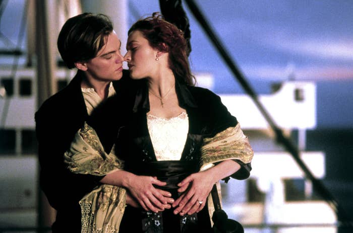 A couple embraces on a ship's deck. The scene is from a movie involving romance and drama at sea