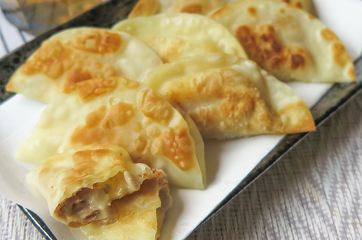 焼き餃子が皿に盛られている。隣にはグラスが置かれている。