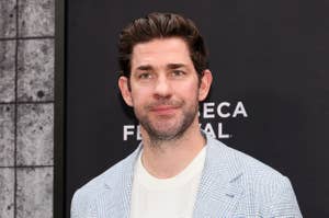 Man in a light checked suit and white shirt at a film festival event. Simple background with festival logo partially visible