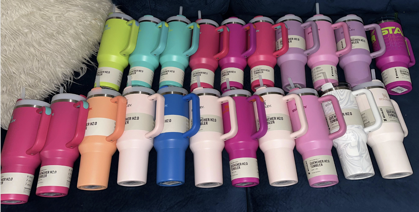 Several insulated water bottles are neatly arranged on a couch, each in various colors and shades