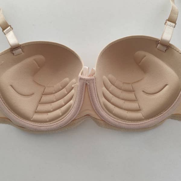 A bra with a unique padding design resembling hands placed inside the cups