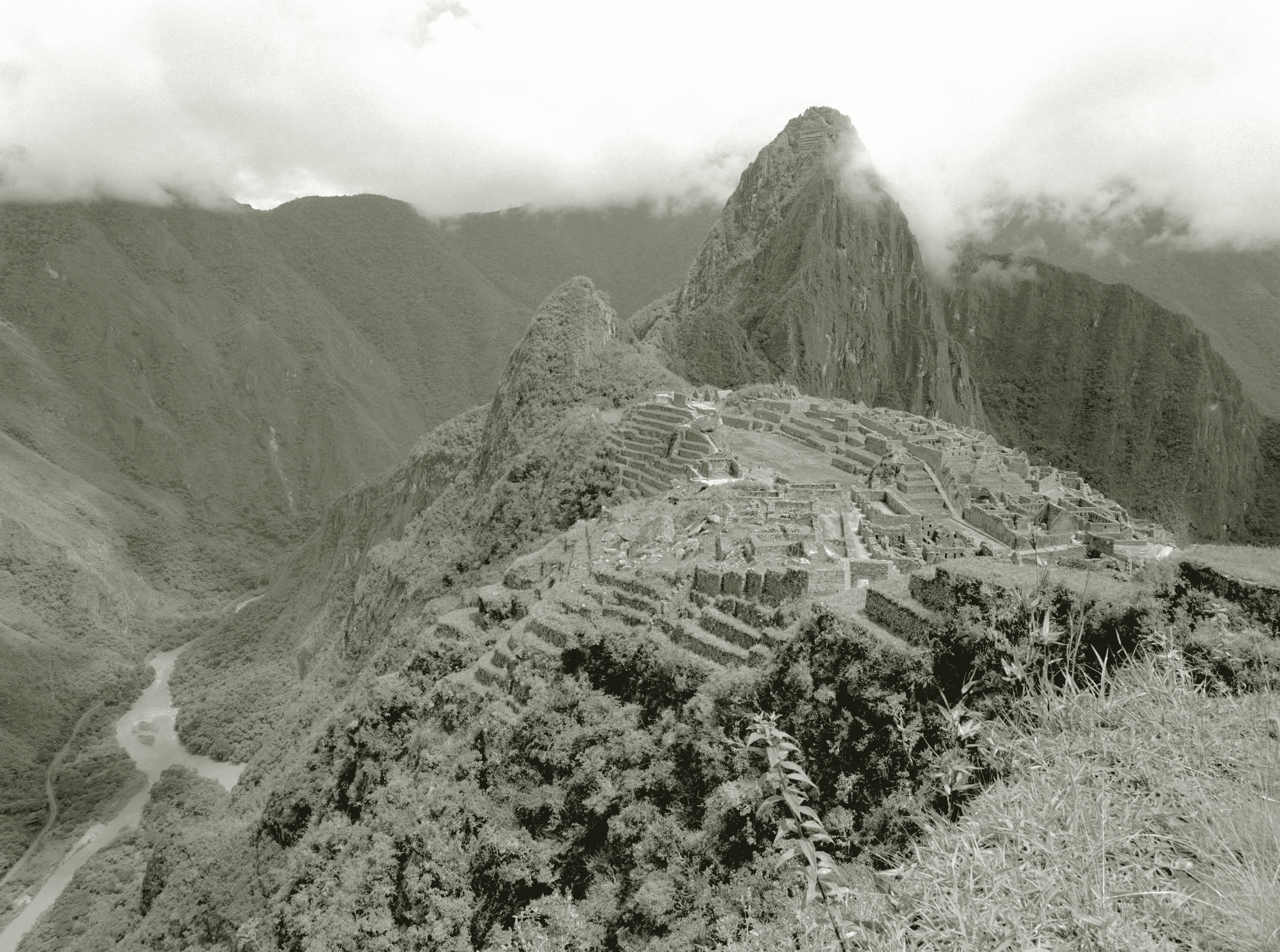 Historic Machu Picchu site with ancient stone structures and terraces against a mountainous backdrop shrouded in clouds