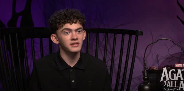 Joe Locke seated in an interview setting for a Marvel-related program, &quot;Agatha: All&quot;