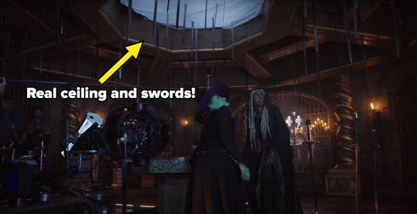 Behind-the-scenes of a fantasy film set with actors dressed as a witch and a mystical figure, surrounded by camera equipment