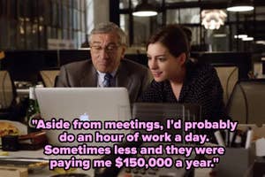 Two people in an office, one older in a suit and the other younger in a casual outfit, look at a laptop together, appearing focused and engaged