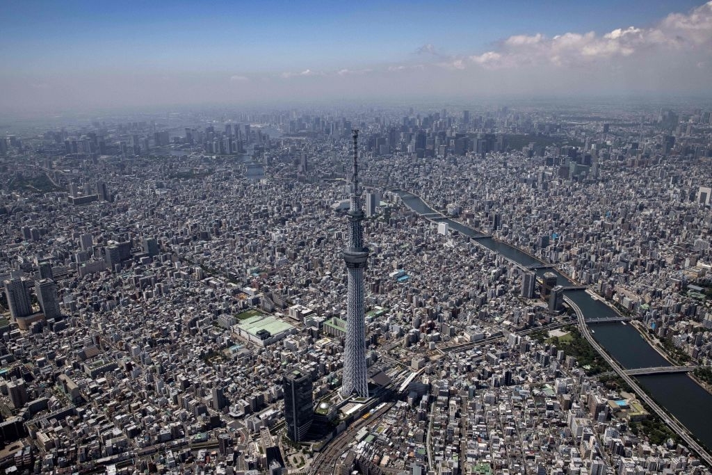 Aerial view of Tokyo with the prominent Tokyo Skytree tower surrounded by urban buildings and intersecting rivers