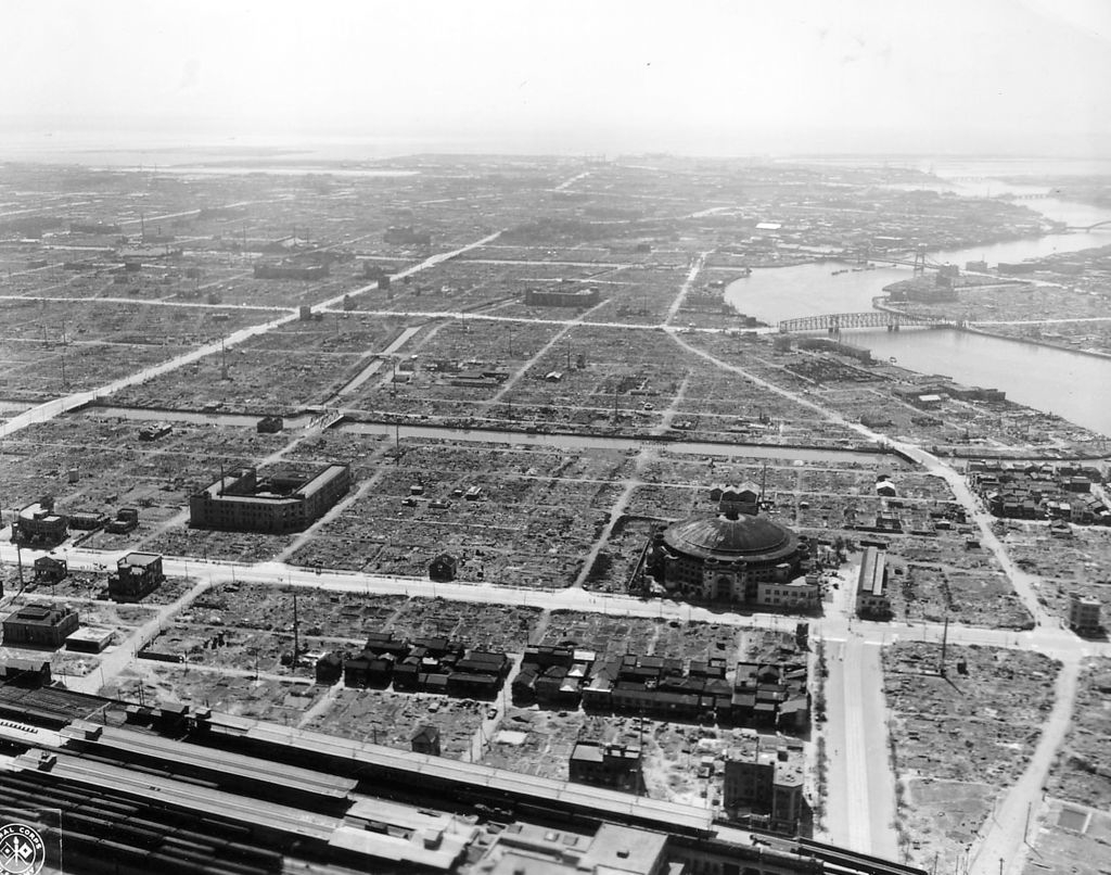 Aerial view of an urban landscape with widespread destruction. Few buildings stand amidst debris, indicating massive damage, likely from a disaster