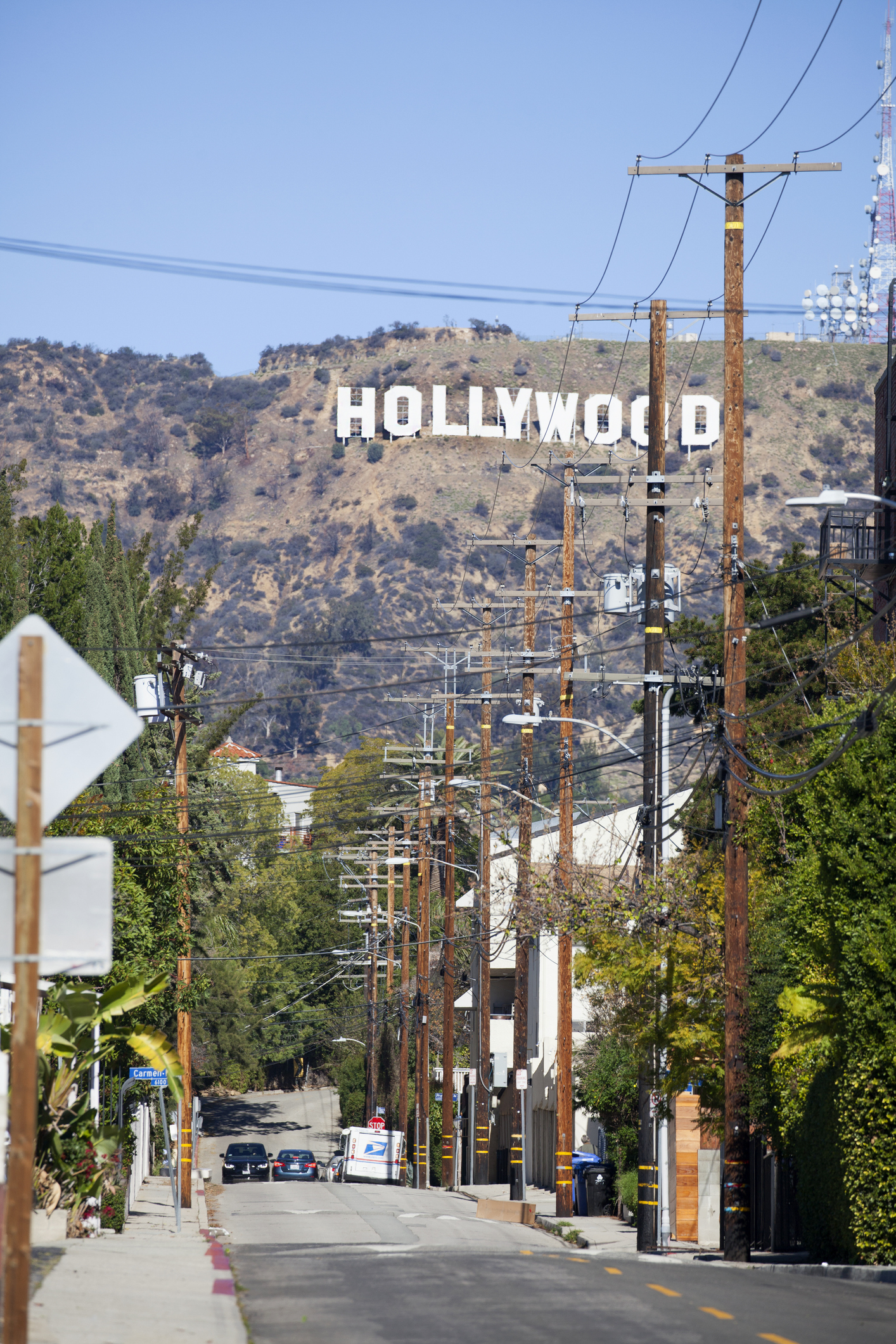 View of the Hollywood sign from a city street lined with telephone poles and trees