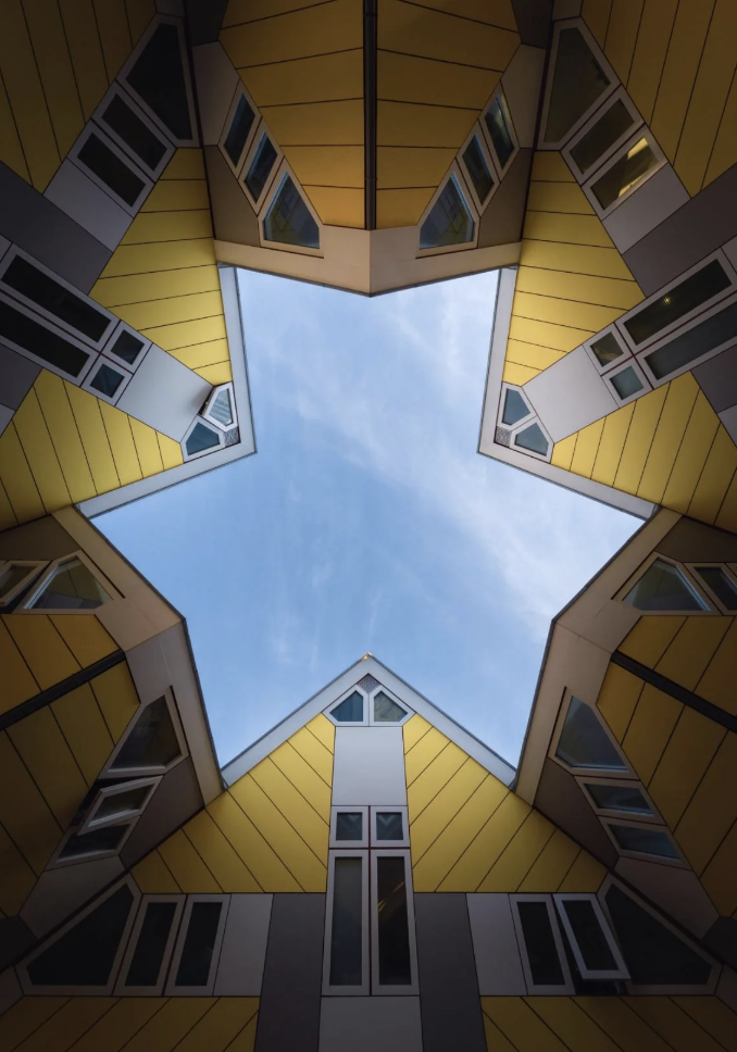 Looking up at the sky through a star-shaped gap formed by modern, geometric buildings with angular roofs and windows