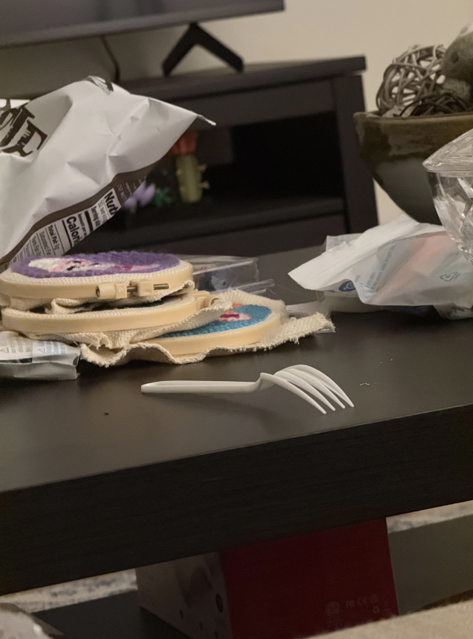 Crafting supplies and cookie decorations on a coffee table, with a plastic fork in the foreground