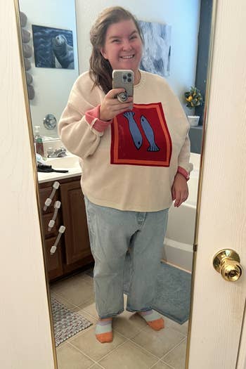 Person successful a cozy sweater with a food plan and escaped jeans, taking a reflector selfie successful a bathroom