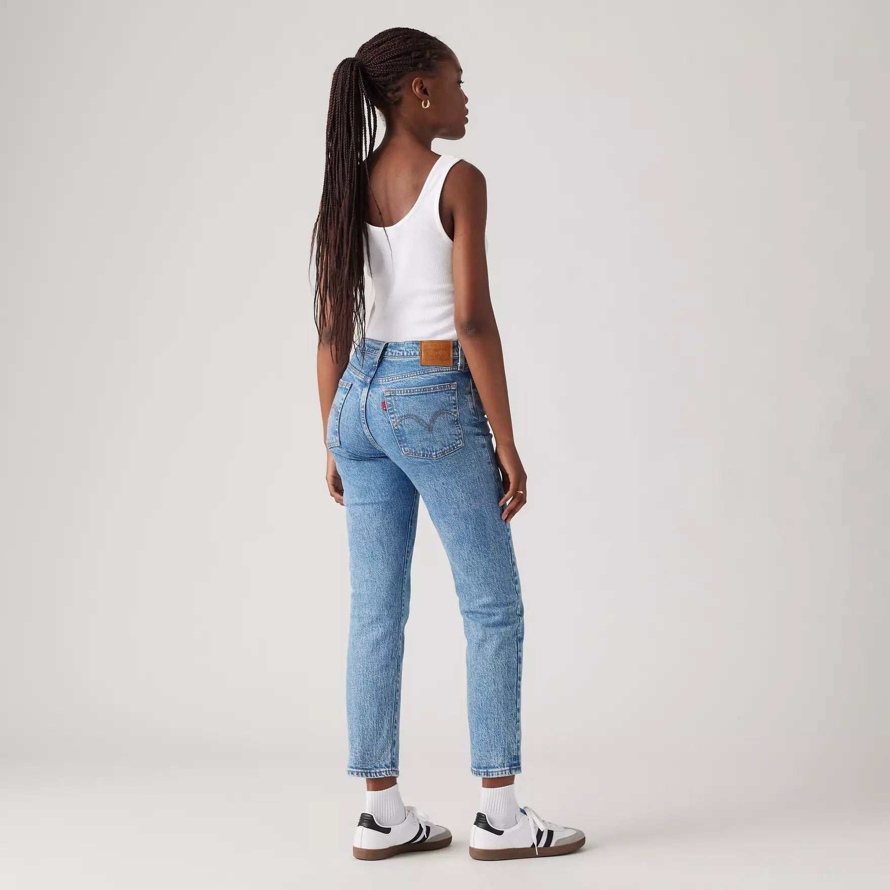 Person wearing a achromatic  vessel  top, bluish  jeans, and sneakers, facing away. Image utilized  successful  a buying  context
