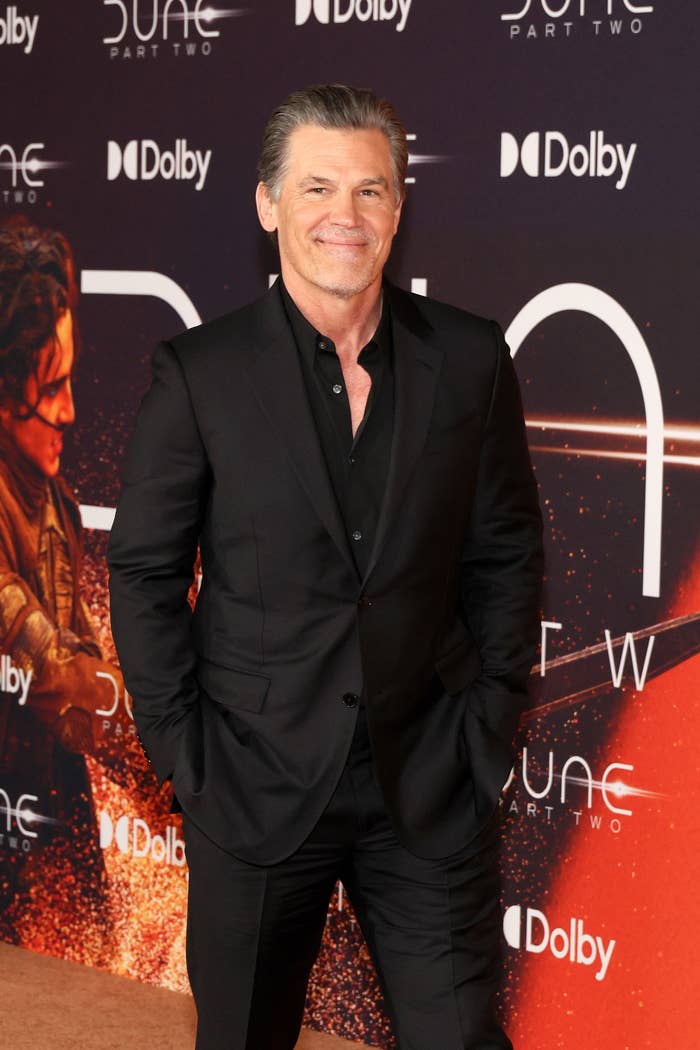 Josh Brolin in a stylish black suit smiling at a 