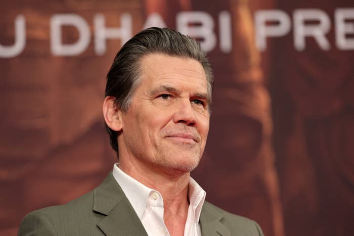 Josh Brolin in a suit smiling at an event with 