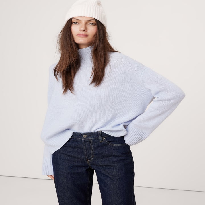 A person wearing a cozy knit sweater, jeans, and a beanie, posing casually. Perfect for winter fashion shopping inspiration