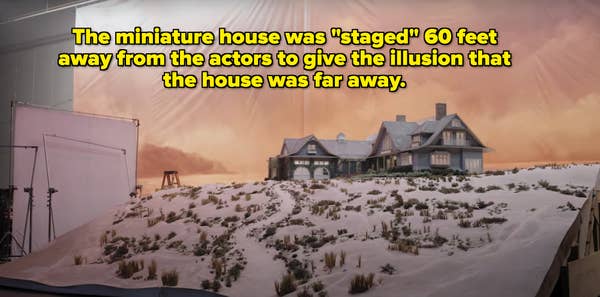 Set of a snowy miniature landscape with a detailed model house, used in TV or movie production. Studio lights and backdrop visible