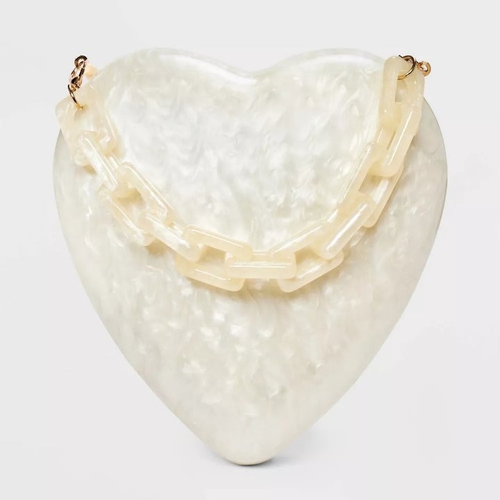 Heart-shaped clutch with a textured surface and chain strap, featured for shopping purposes