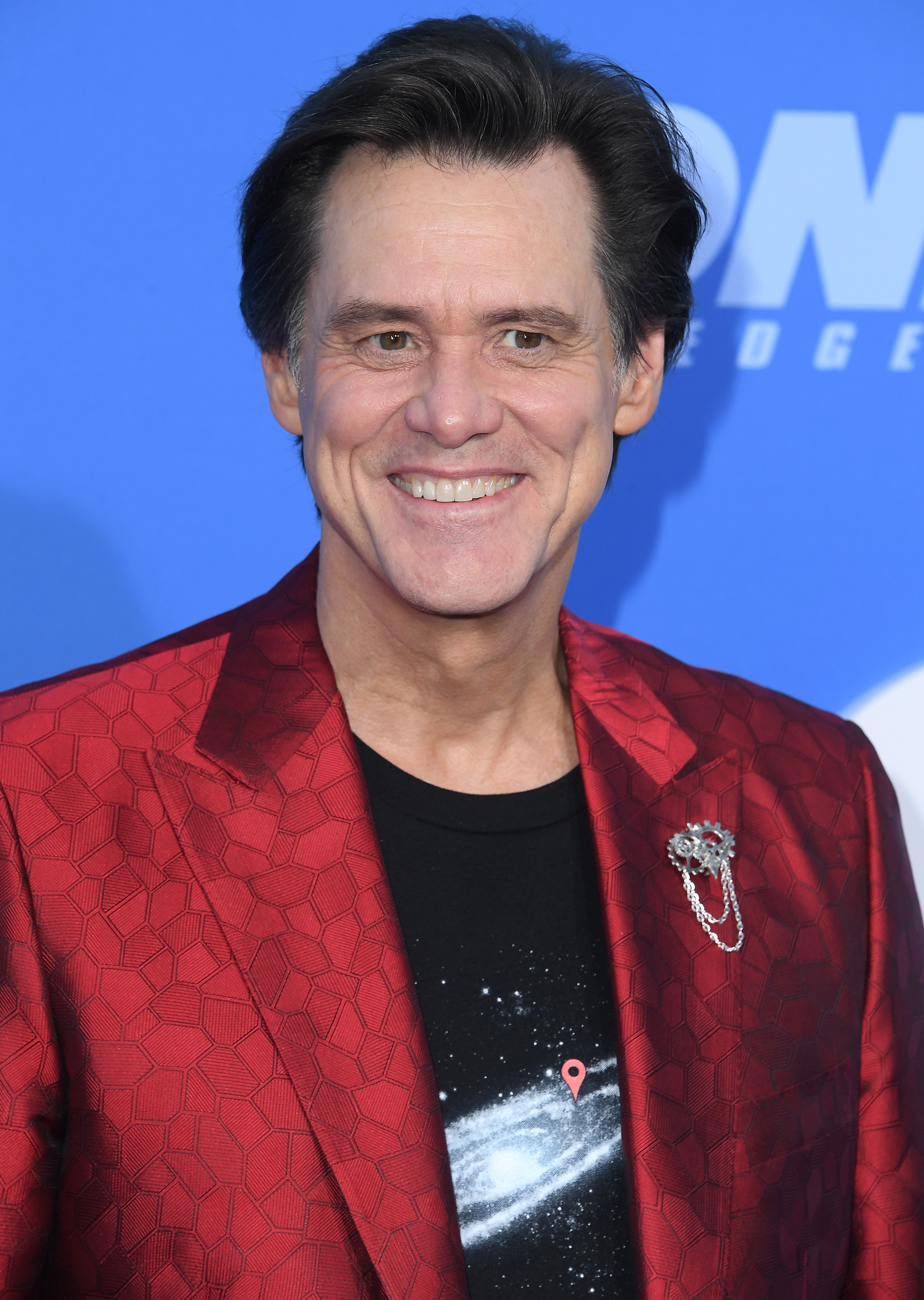 Person in a patterned suit jacket and galaxy-themed shirt, smiling at an event