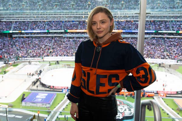 A person stands in a stadium overlooking a hockey rink, wearing a hockey jersey with the number 30 and the name &quot;EAGLES.&quot;