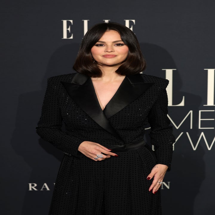 Person in a sophisticated black suit with subtle embellishments on a red carpet at a celebrity event