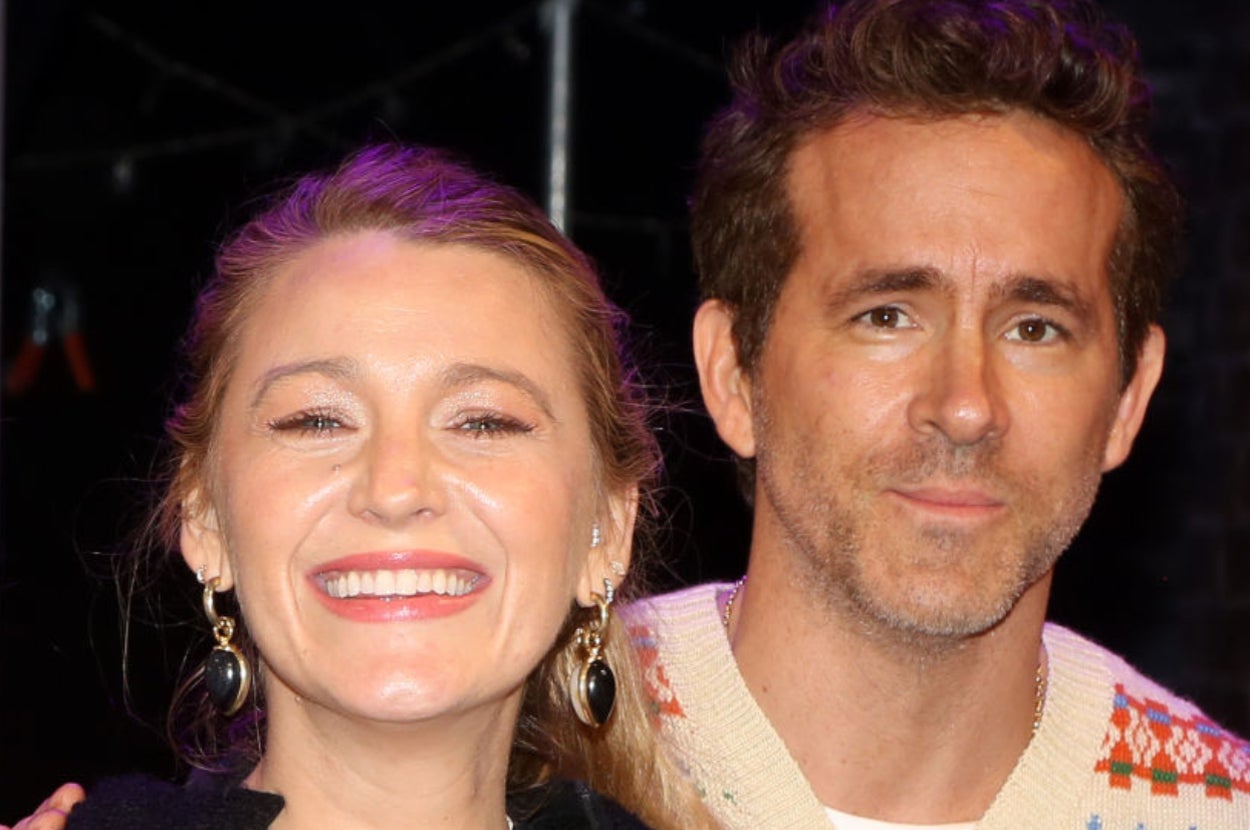 Two people smiling; one is wearing a knitted sweater, and the other has a black outfit with large earrings