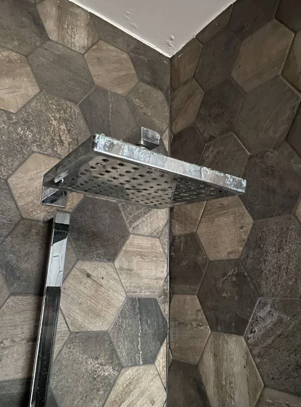 Reddit post discussing how to replace a rainfall showerhead with a standard one. Image shows an installed showerhead with a stone tile backdrop