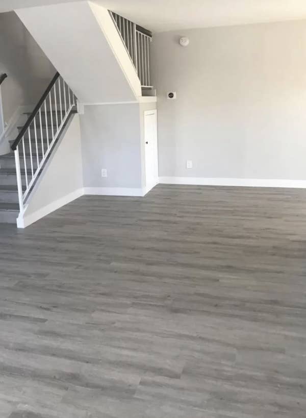 Screenshot of a Reddit discussion about interior decorating with a focus on the use of grey wood floors and white walls