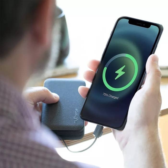 A person holds a charging phone showing 75% battery, connected to a portable power bank, highlighting mobile charging convenience for shopping