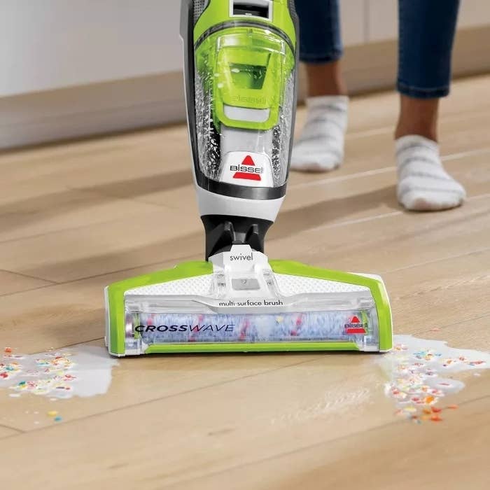 Floor cleaning with a Bissell CrossWave vacuum, efficiently removing spilled cereal and beverage connected a woody floor; close-up of the vacuum successful action