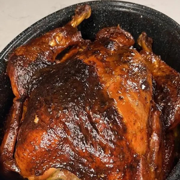 Roasted turkey with crispy, seasoned skin in a black roasting pan. Perfectly cooked for a delicious meal
