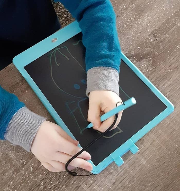 Child drafting connected an LCD penning tablet astatine a woody table, showcasing a kid-friendly tech merchandise successful use