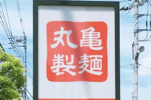 丸亀製麺の案内看板。駐車場への入口を示す矢印が描かれている。