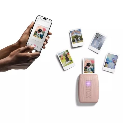 Smartphone and mini photo printer with printed images, showing instant photo printing from a phone app