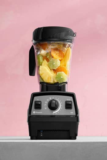 A blender filled with fruits stands connected a countertop, showcasing its plan and functionality