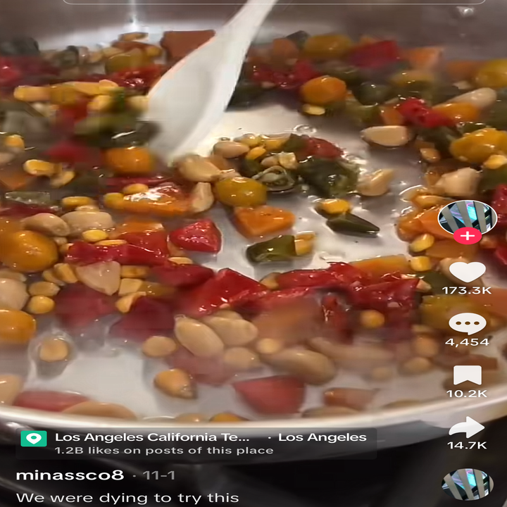 A pan filled with cooking vegetables and nuts being stirred with a spoon. Overlay text indicates social media engagement details