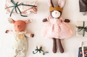 Stuffed animal toys, including a pink dress bunny and a cloth-wrapped package, displayed for a shopping article