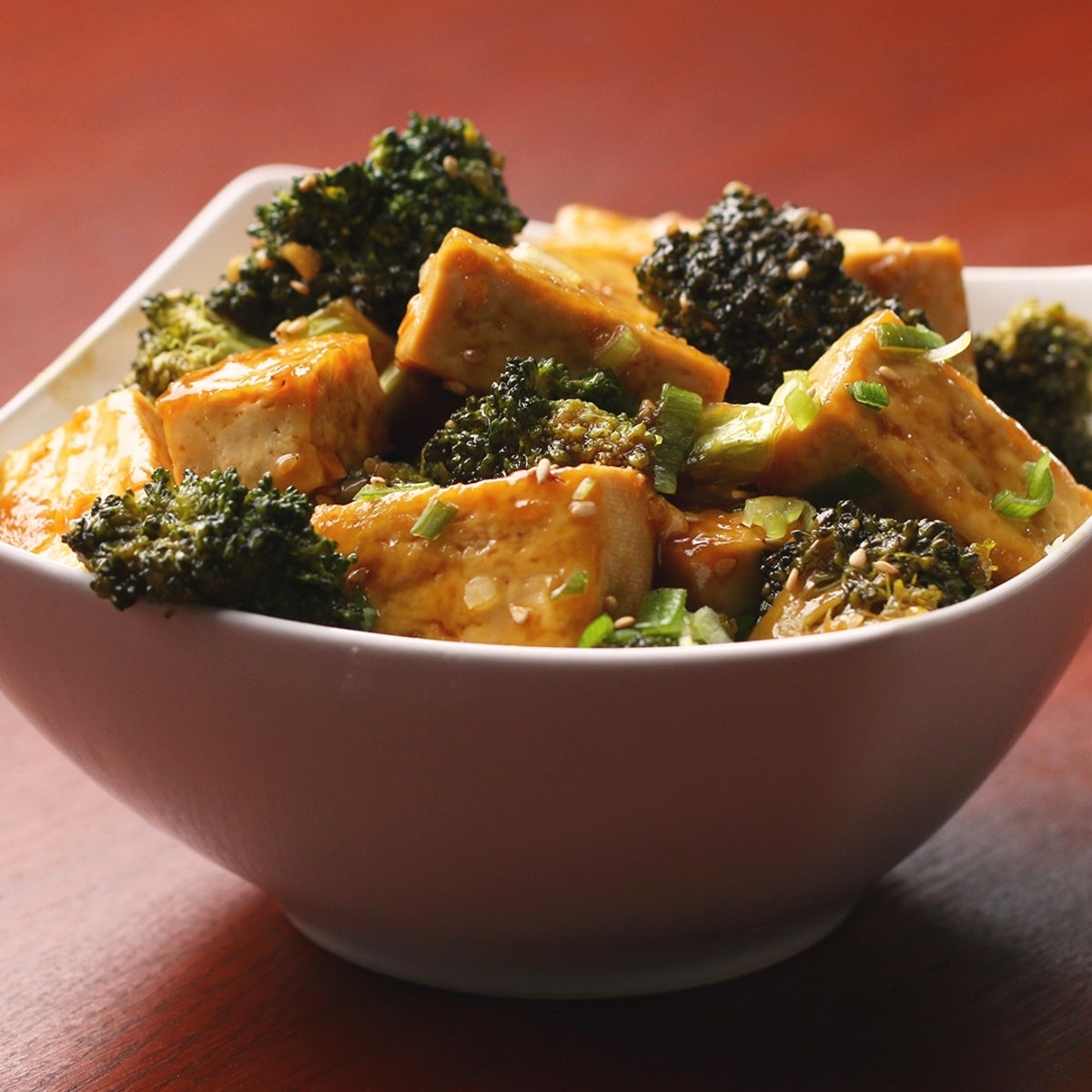 Bowl of tofu and broccoli stir-fry garnished with green onions