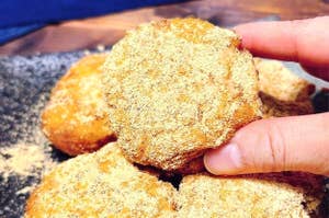 きなこがまぶされた数枚のドーナッツを手に取る様子。